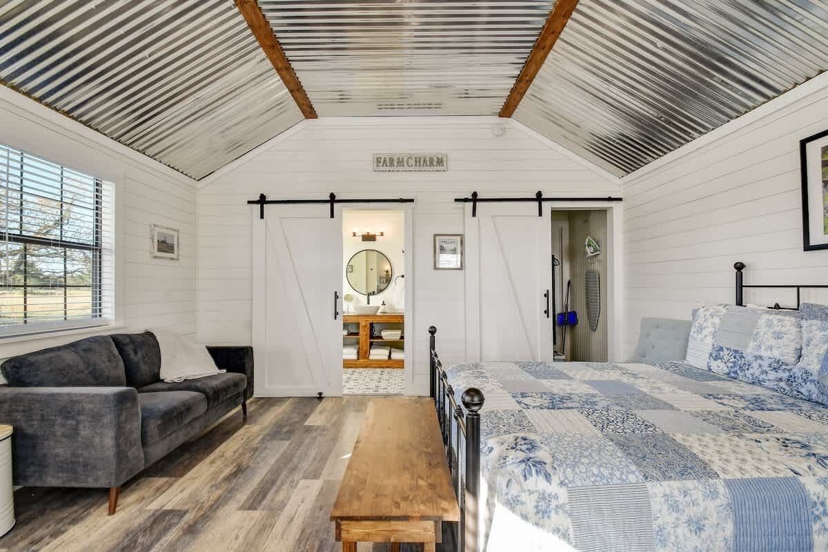 A bedroom with a bed, a bench, a sofa, and a window.