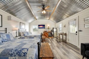 A spacious attic bedroom with two beds, a wooden dining table, and a kitchenette.