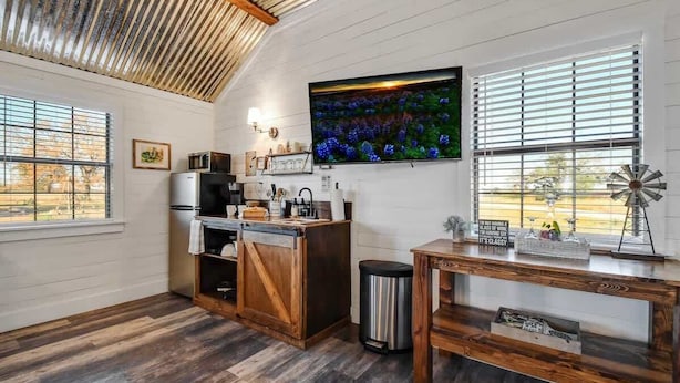 Une cuisine avec un plafond en bois, une grande télévision, une décoration représentant un moulin à vent et une table en bois rustique.