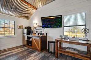 Une cuisine avec un plafond en bois, une grande télévision, une décoration représentant un moulin à vent et une table en bois rustique.