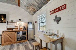 A compact kitchen with a wooden island, a refrigerator, and a window with blinds.