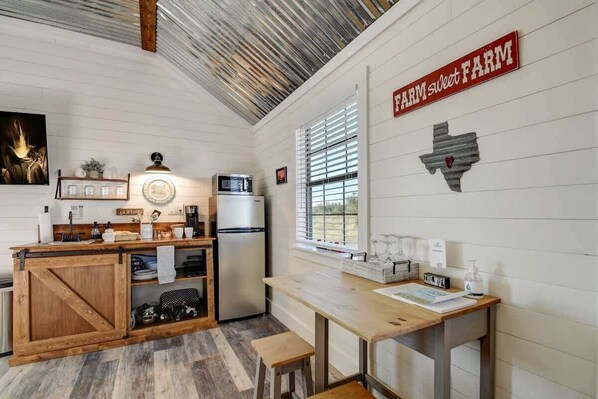 A kitchen with a wooden island, a refrigerator, and a window with blinds.