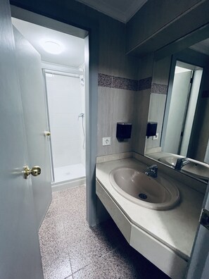 A bathroom with a sink, mirror, and shower. - Hostel 165 (Madrid)