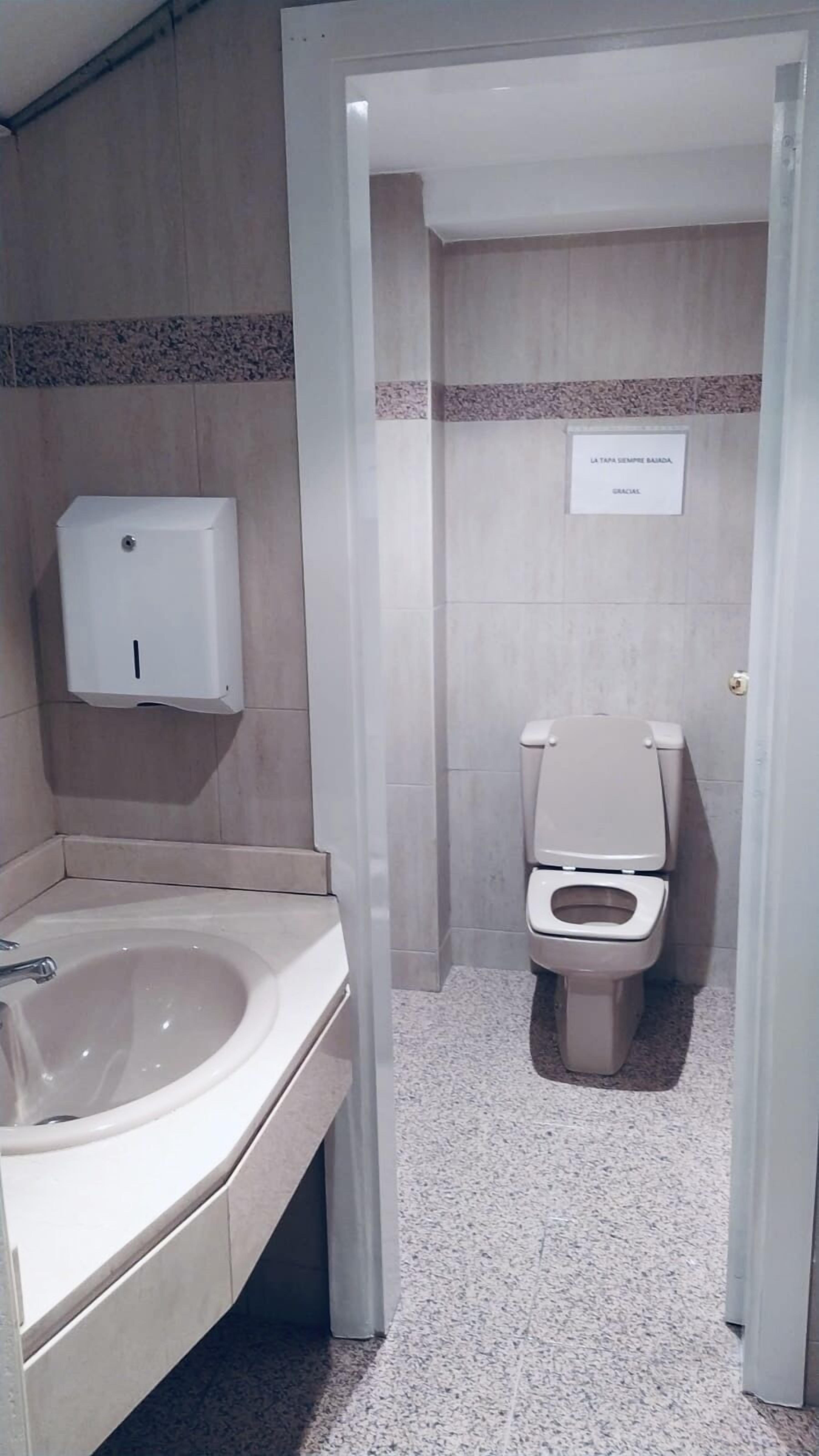 Un baño con lavamanos, inodoro y secamanos.