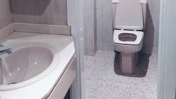 Un baño con lavamanos, inodoro y secamanos.