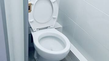 Une salle de bain moderne avec des toilettes blanches, des carreaux gris et un sol en béton.