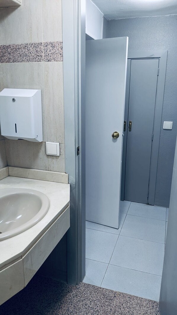 A bathroom with a sink, a hand dryer, and two doors. - Hostel 165 (Madrid)