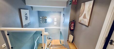 A staircase leading to a landing with a fire extinguisher and a first aid kit on the wall.