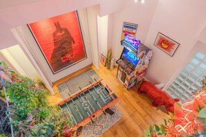 A room with a foosball table, a large Batman poster, a neon sign, and a red pig decoration.