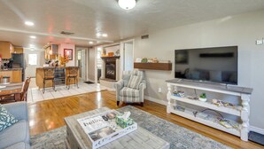 A spacious living room with a large TV, a fireplace, and a dining area with a kitchen in the background. - 2 Mi to Dtwn: Grand Junction Home w/ Hot Tub (Grand Junction)