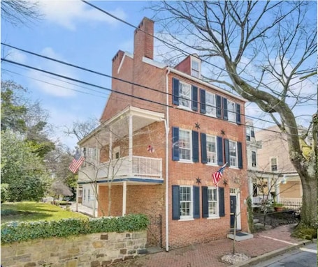 A two-story brick building with a balcony, American flags, and a stone wall.