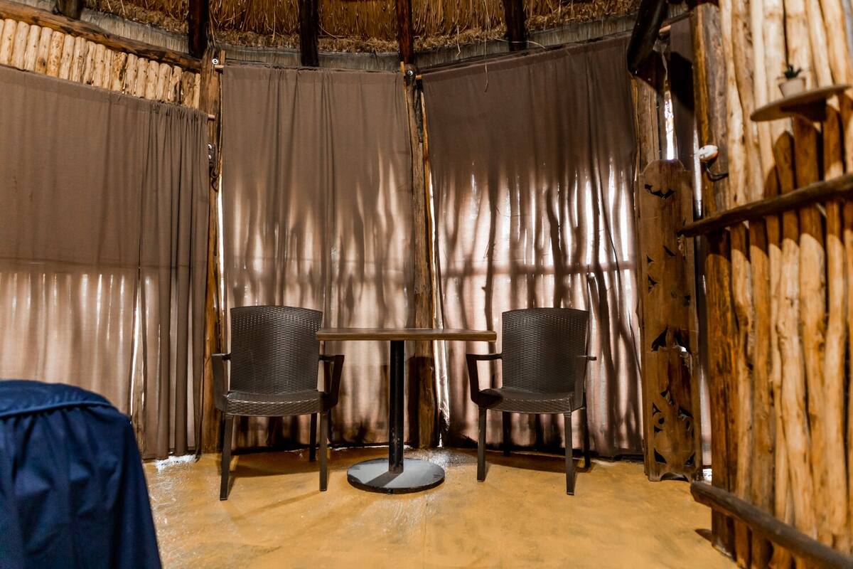 A rustic wooden room with two wicker chairs and a small table.
