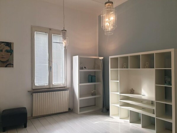 A modern room with a white radiator, a black bench, and a white shelving unit.