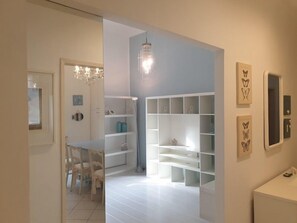 A modern, minimalist room with white walls, a chandelier, and built-in shelving.