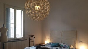 A bedroom with a bed, a radiator, a window with blinds, a hanging light fixture, and a mannequin. - Cleo Tulipano (Falconara Marittima)