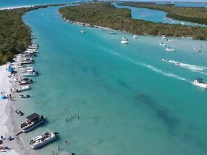 An aerial view of a coastal area with boats docked along the shore and a clear blue sea. - Sunset Point Marina - Dolphin (Manasota Key)