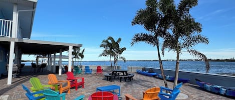 A patio area with colorful Adirondack chairs, a covered seating area, and a view of the sea.