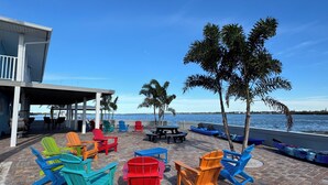 A patio area with colorful Adirondack chairs, a covered seating area, and a view of the sea. - Sunset Point Marina - Starfish (Manasota Key)