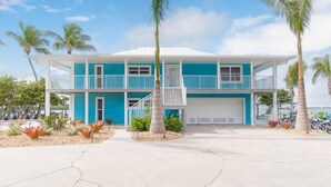 A two-story building with a blue exterior and white accents, featuring a balcony and a covered entrance. - Sunset Point Marina - Starfish (Manasota Key)