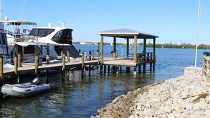 A marina with boats docked, a covered pier, and a rocky shoreline. - Sunset Point Marina - Starfish (Manasota Key)