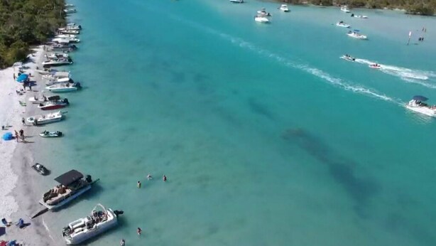 An aerial view of a coastal area with boats docked along the shore and a clear blue sea. - Sunset Point Marina - Starfish (Manasota Key)