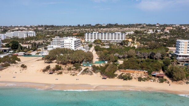 An aerial view of a coastal area with a beach, several buildings, and a clear blue sea. - Sanders Florida - Charming Studio With Shared Pool (Ayia Napa)