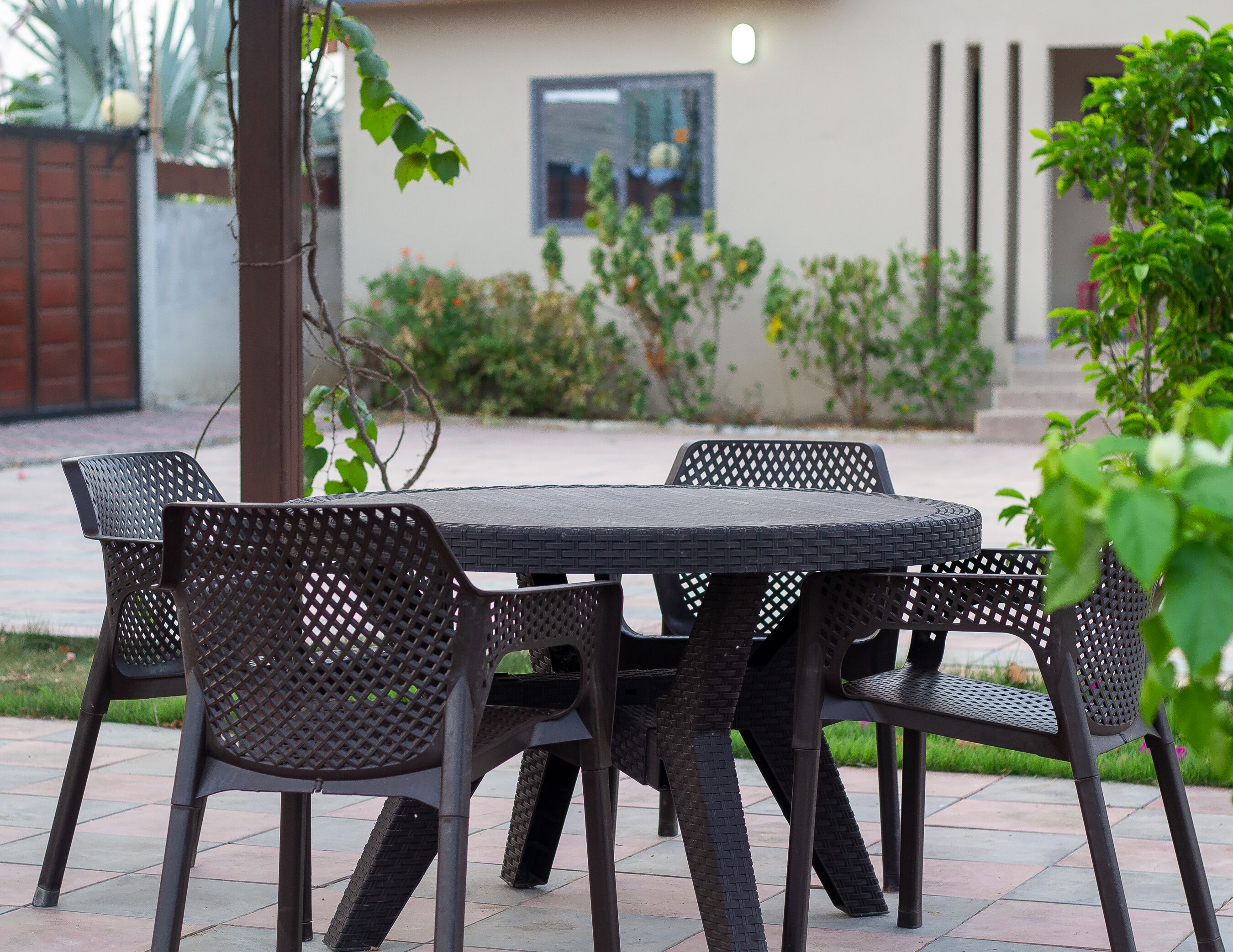 Un patio al aire libre con una mesa redonda y cuatro sillas.