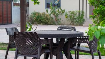 Un patio al aire libre con una mesa redonda y cuatro sillas.