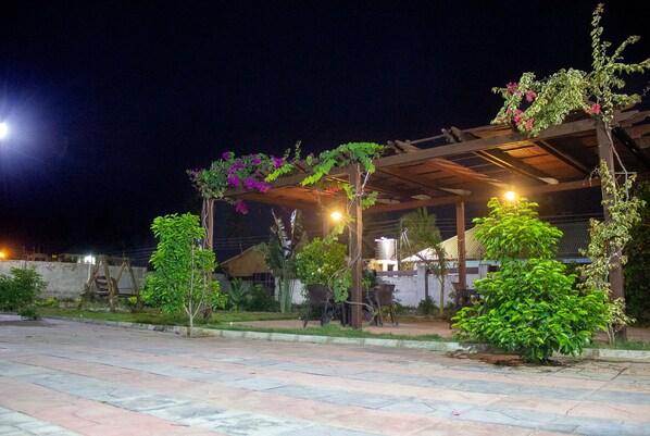 Un espacio al aire libre con una pérgola, asientos y vegetación.