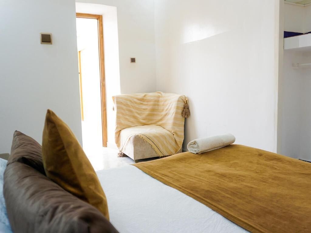 A bedroom with a bed, a chair, and a wardrobe.