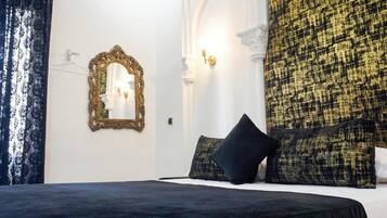 A bedroom with a bed, a mirror, and a patterned wall.