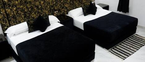 A hotel room with two beds, a decorative headboard, a black and white striped rug, and a white tiled floor.
