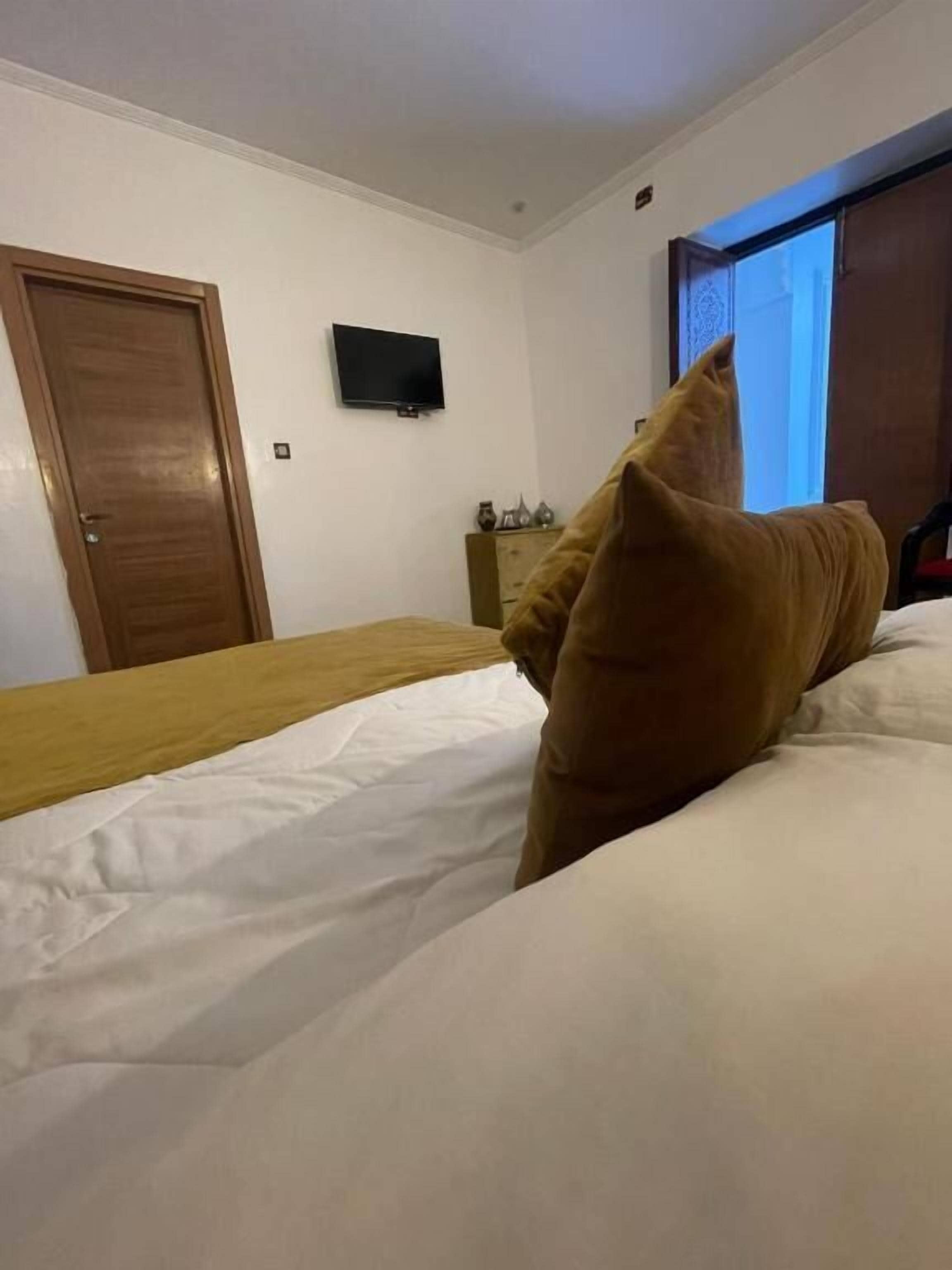 Une chambre à coucher avec un lit, un téléviseur fixé au mur, une porte en bois et une fenêtre donnant sur un beau paysage.
