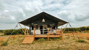 A tented accommodation with a wooden deck, a staircase leading to the entrance, and a hanging light fixture. - Owls Nest (Walsingham)