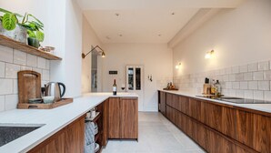 A modern kitchen with wooden cabinets, a white countertop, and a tiled backsplash. - Spacious Edwardian 5-bed House, steps from Beach (Kent)