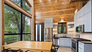 Una cocina moderna con vigas de madera en el techo, ventanas amplias y electrodomésticos de acero inoxidable.