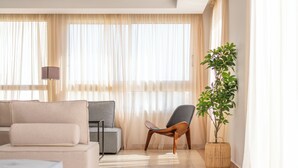 A modern living room with a sofa, armchair, and a potted plant. - Sanders Florida - Modest Studio With Sea View (Ayia Napa)
