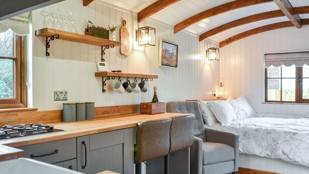 A cozy kitchen with wooden beams, a bar area, and a bed with a floral bedspread. - 1 bedroom accommodation in Pocklington (Pocklington)