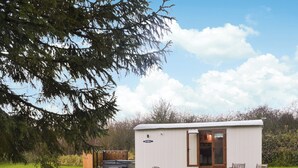 A small, single-story mobile home with a white exterior, a wooden deck, and a patio area with two chairs. - 1 bedroom accommodation in Pocklington (Pocklington)