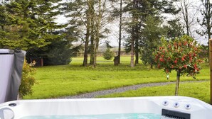 A hot tub in a garden with a grassy area and trees in the background. - 1 bedroom accommodation in Pocklington (Pocklington)