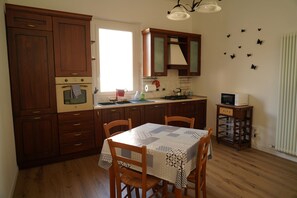 Appartement | Privékeuken | Een koelkast met diepvriezer, een oven, kookgerei, borden en bestek