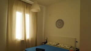 Un dormitorio con cama, mesita de noche, lámpara y un adorno en la pared.