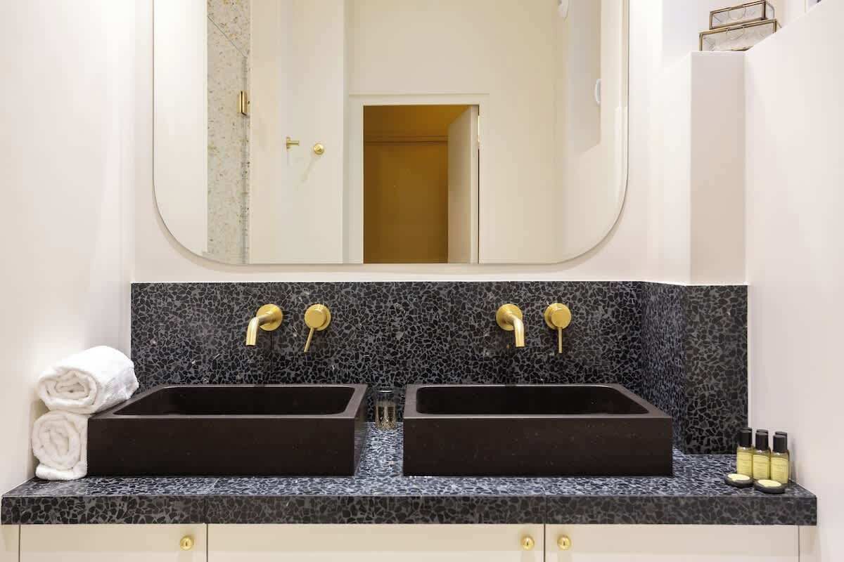 Une salle de bain avec deux lavabos, un grand miroir et un porte-serviettes.