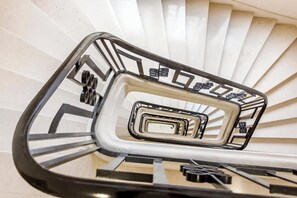 Uma escadaria em espiral com design geométrico e corrimãos de metal.