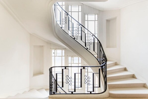 A spiral staircase with a black metal railing and white walls.