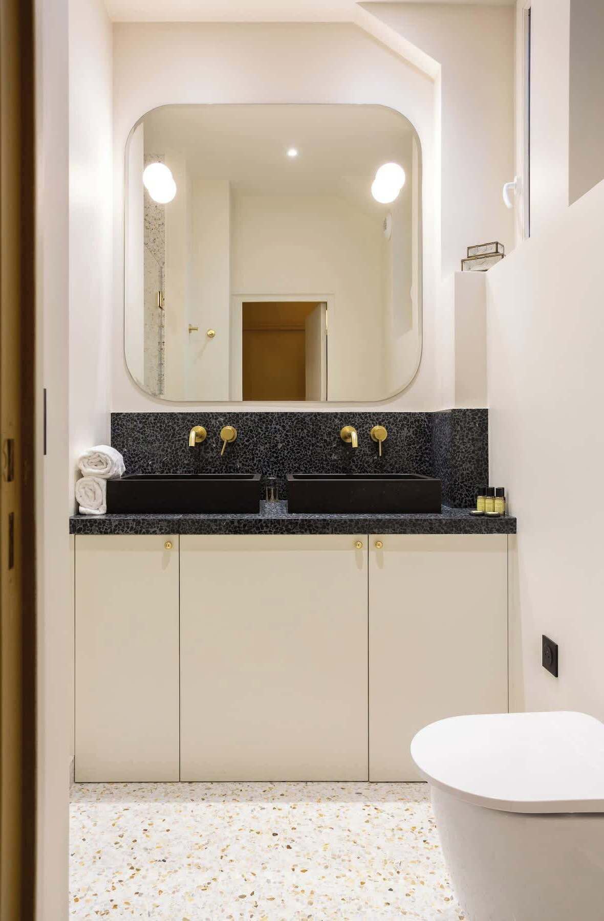 A modern bathroom with a double sink, a large mirror, and a white bathtub.