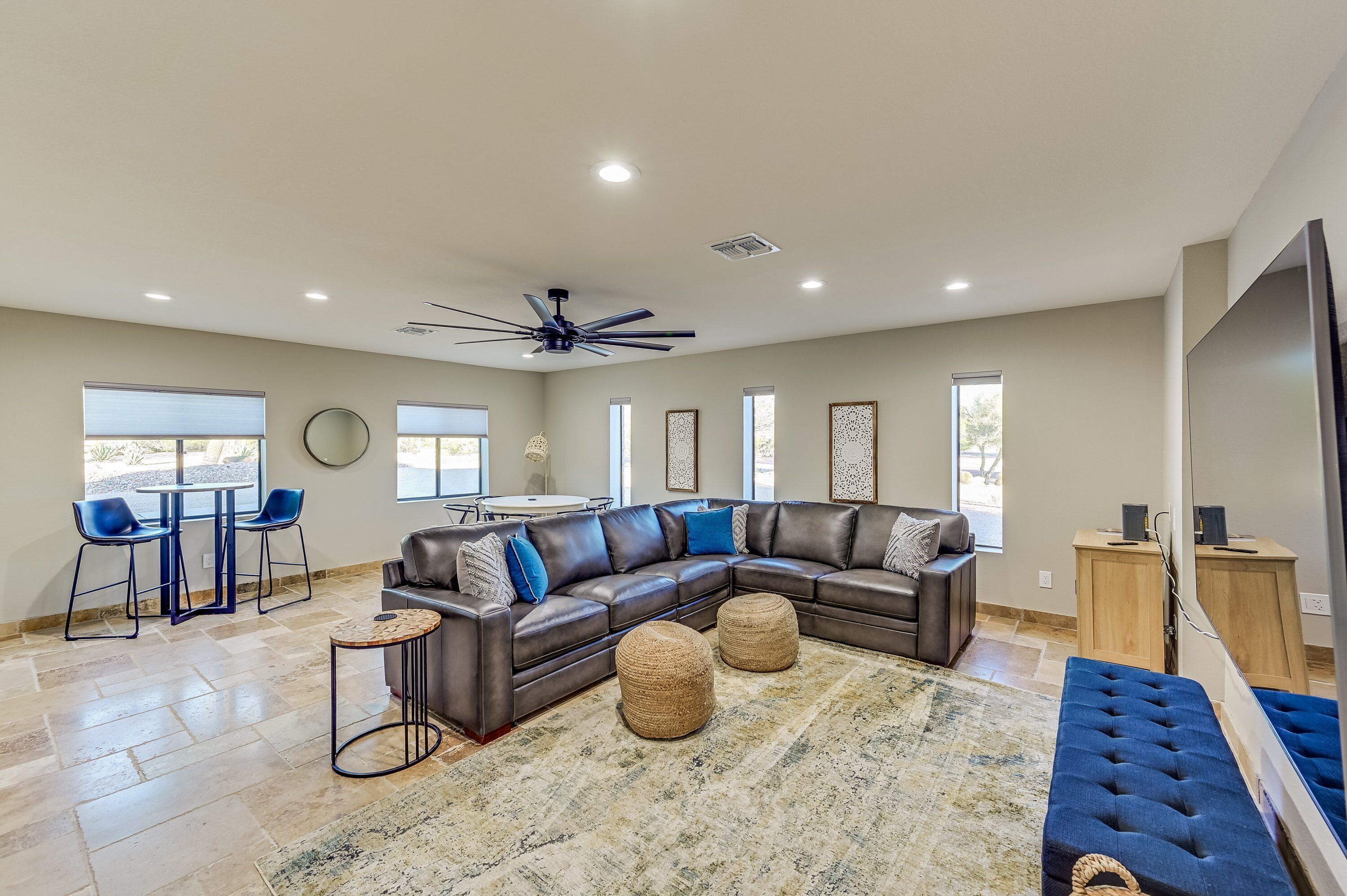 A spacious living room with a large sectional sofa, a ceiling fan, and a dining area with chairs and a table.