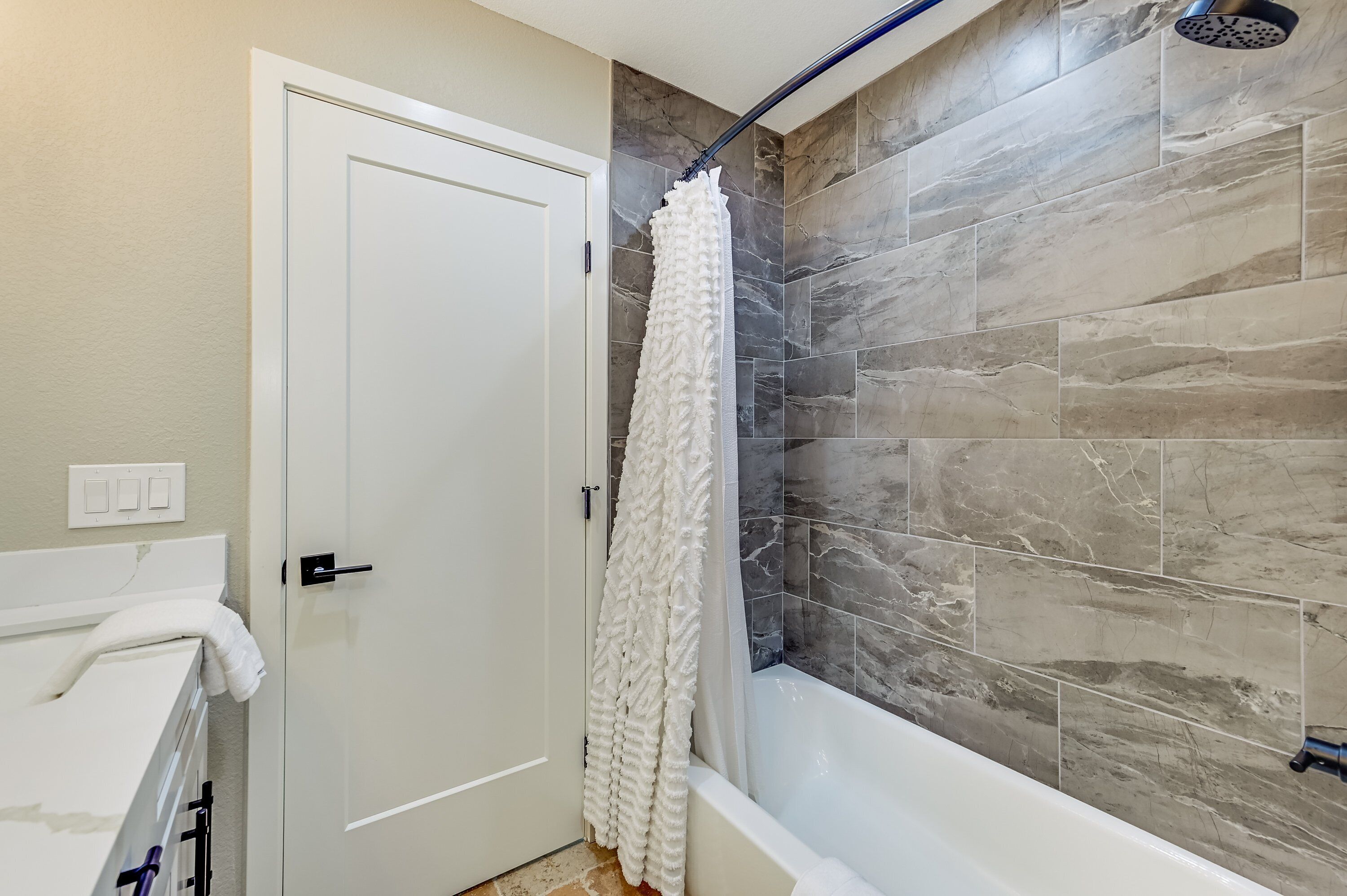 A bathroom with a shower curtain, a bathtub, and a door.