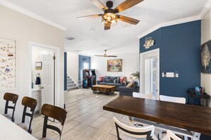 A spacious living area with a dining table, chairs, a sofa, and a ceiling fan.