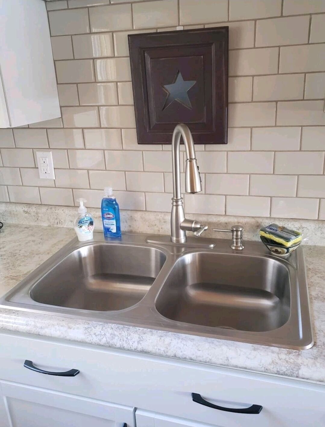 A kitchen with a double stainless steel sink, a faucet, and a cabinet above the sink.